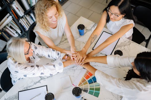 Overhead view of diverse women collaborating in a modern office setting, showing teamwork and unity.